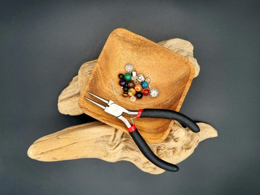 des perles et une pinces dans une coupelle en bois