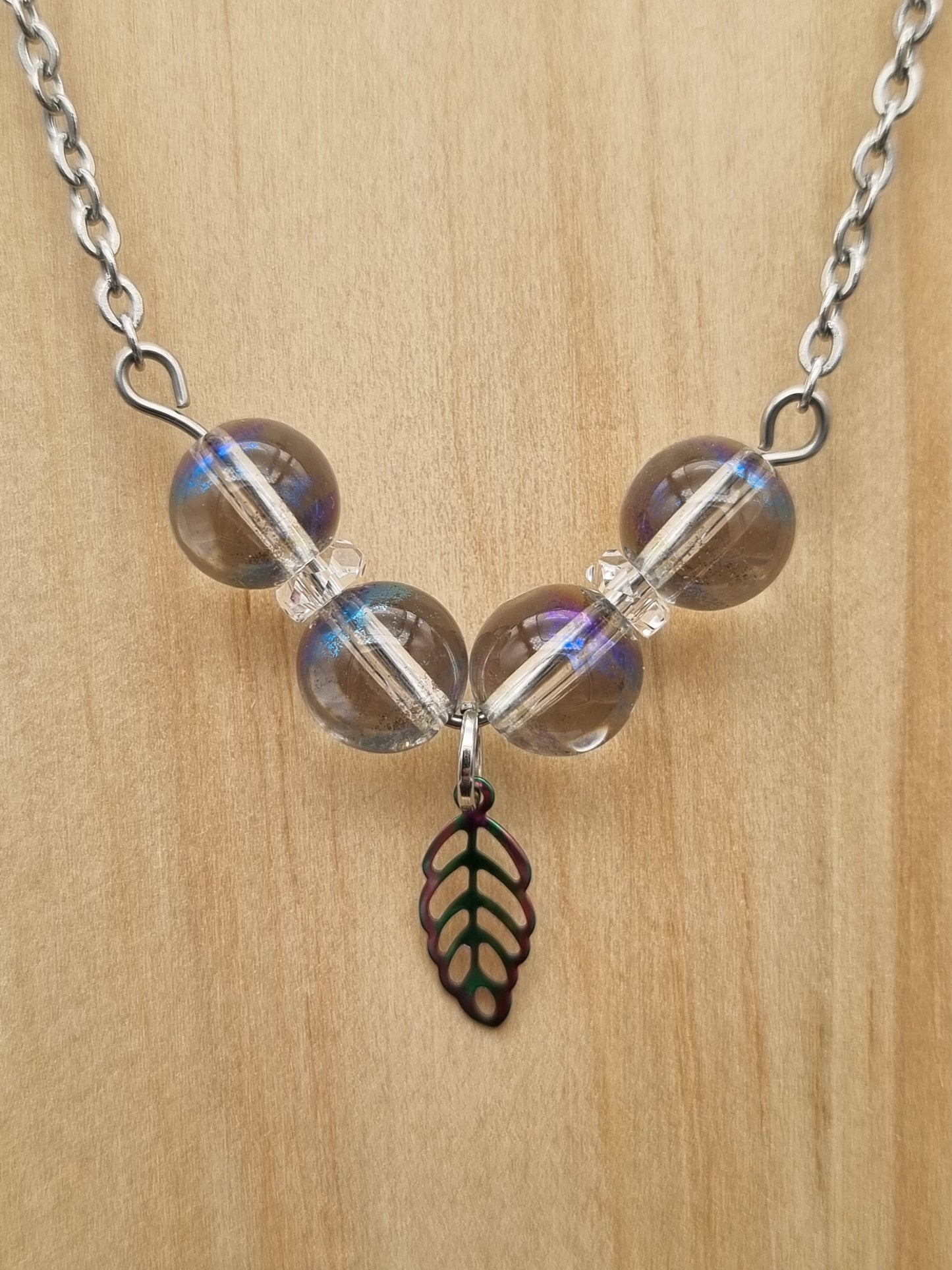 Collier en acier inoxydable avec quatre perles d’aqua aura et une feuille pendante, fait main en Gironde.