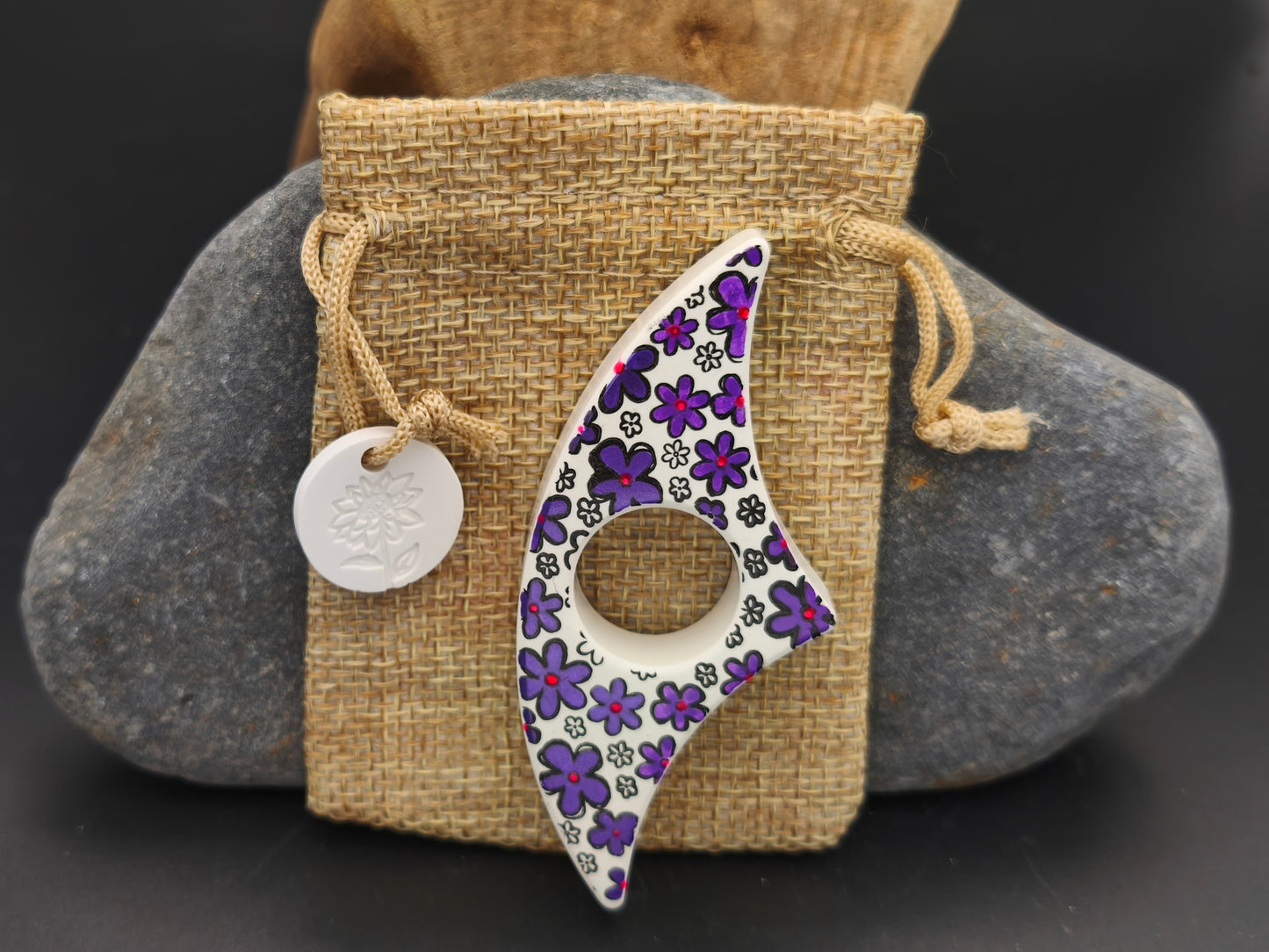 Bague de lecture artisanale Omiralys blanc floral violet avec son pochon en toile de jute et médaille blanche assortie.