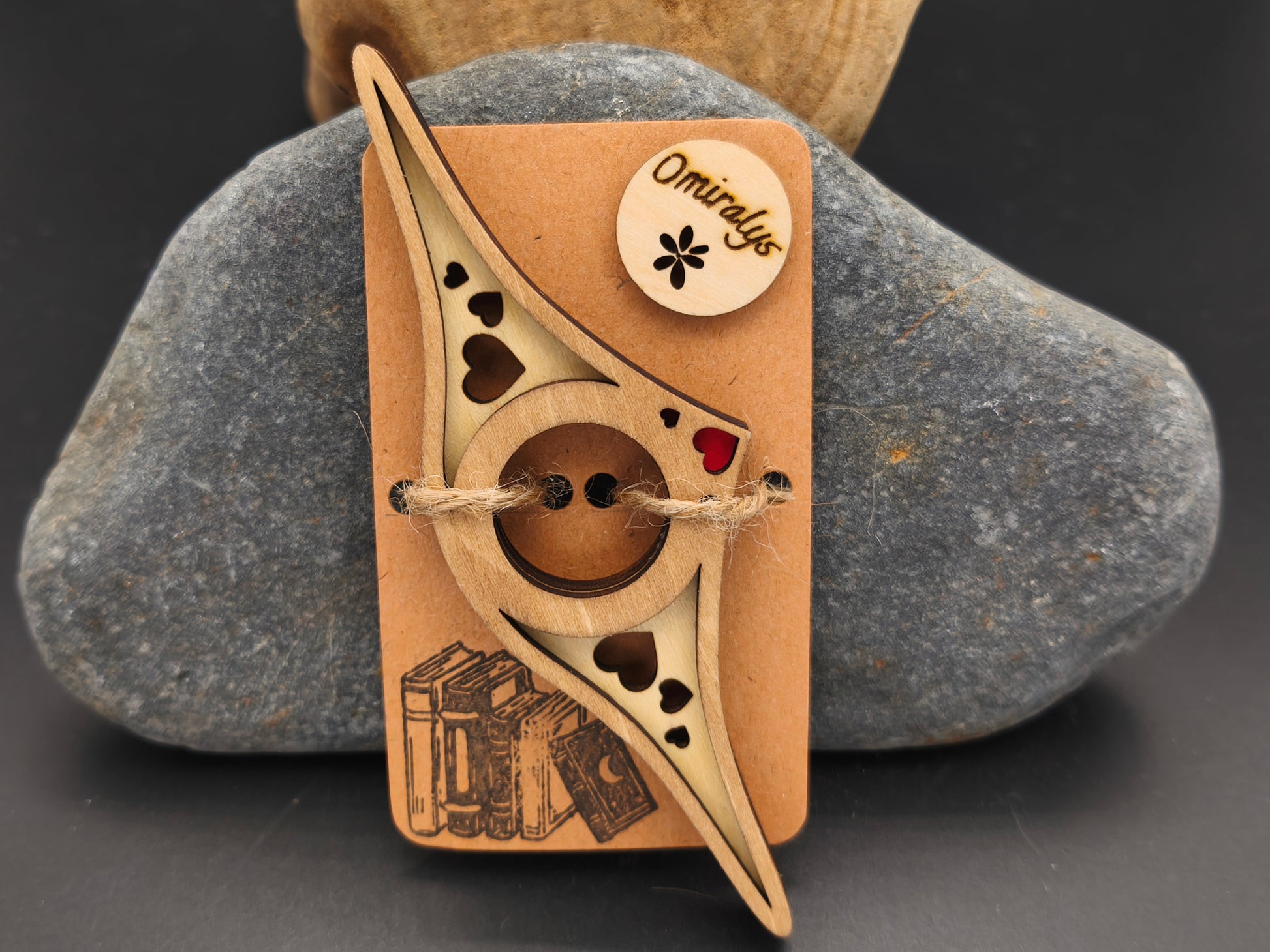 Bague de lecture artisanale Omiralys en bois de tilleul bicolore avec motifs cœurs et trio de petits cœurs rouges en relief 3D sur support kraft.