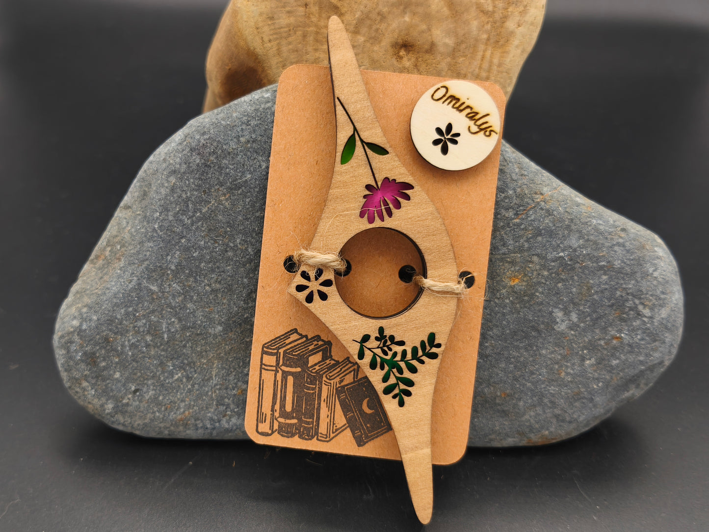 Bague de lecture artisanale Omiralys en bois de tilleul avec fleur rose et feuillage vert en relief 3D sur support kraft.