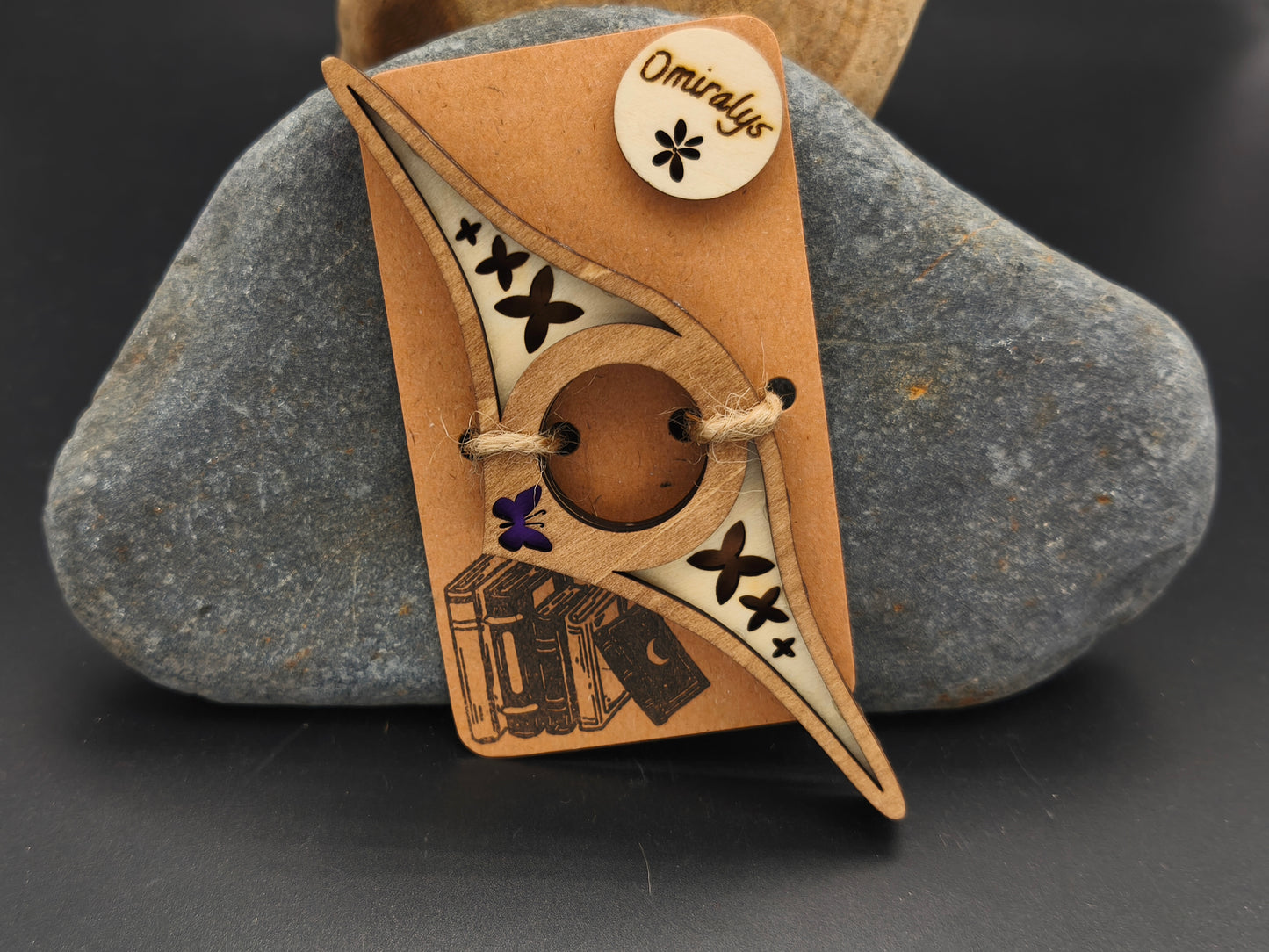 Bague de lecture artisanale Omiralys en bois de tilleul bicolore avec silhouettes de papillons et petit papillon violet en relief 3D sur support kraft.