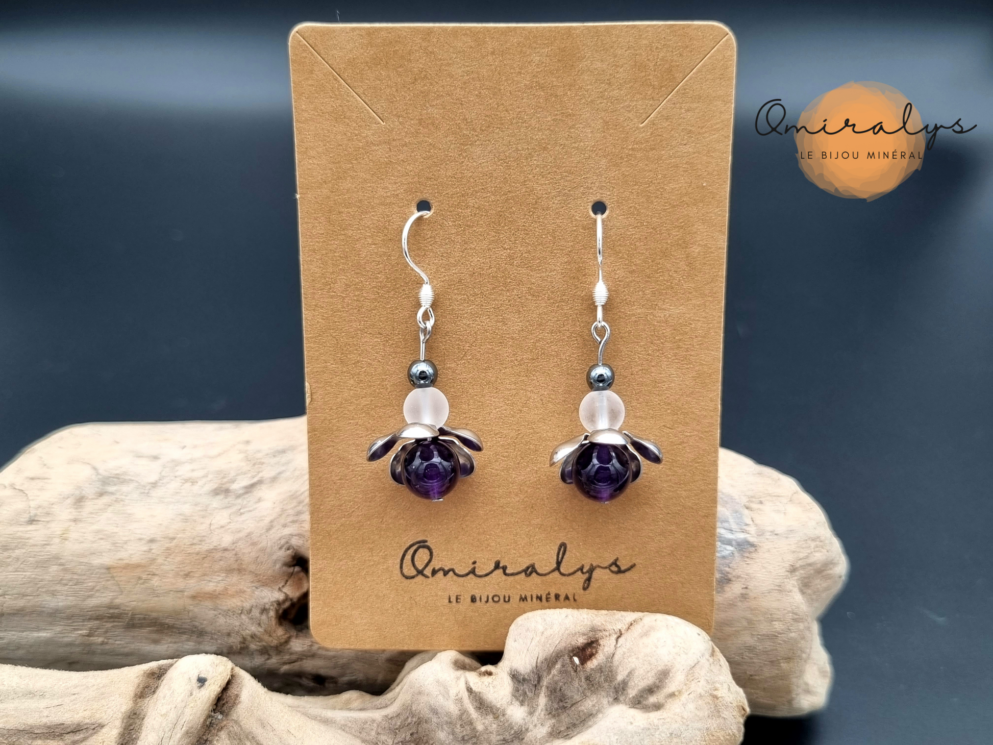 Boucles d'oreilles améthyste, cristal de roche et hématite exposées sur une carte présentoir en carton.