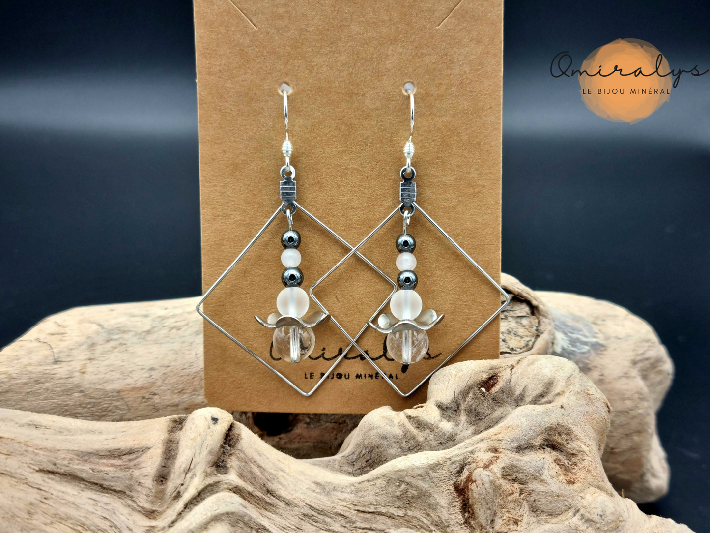 Boucles d'oreilles cristal de roche, hématite et quartz rose  exposées sur une carte présentoir en carton.