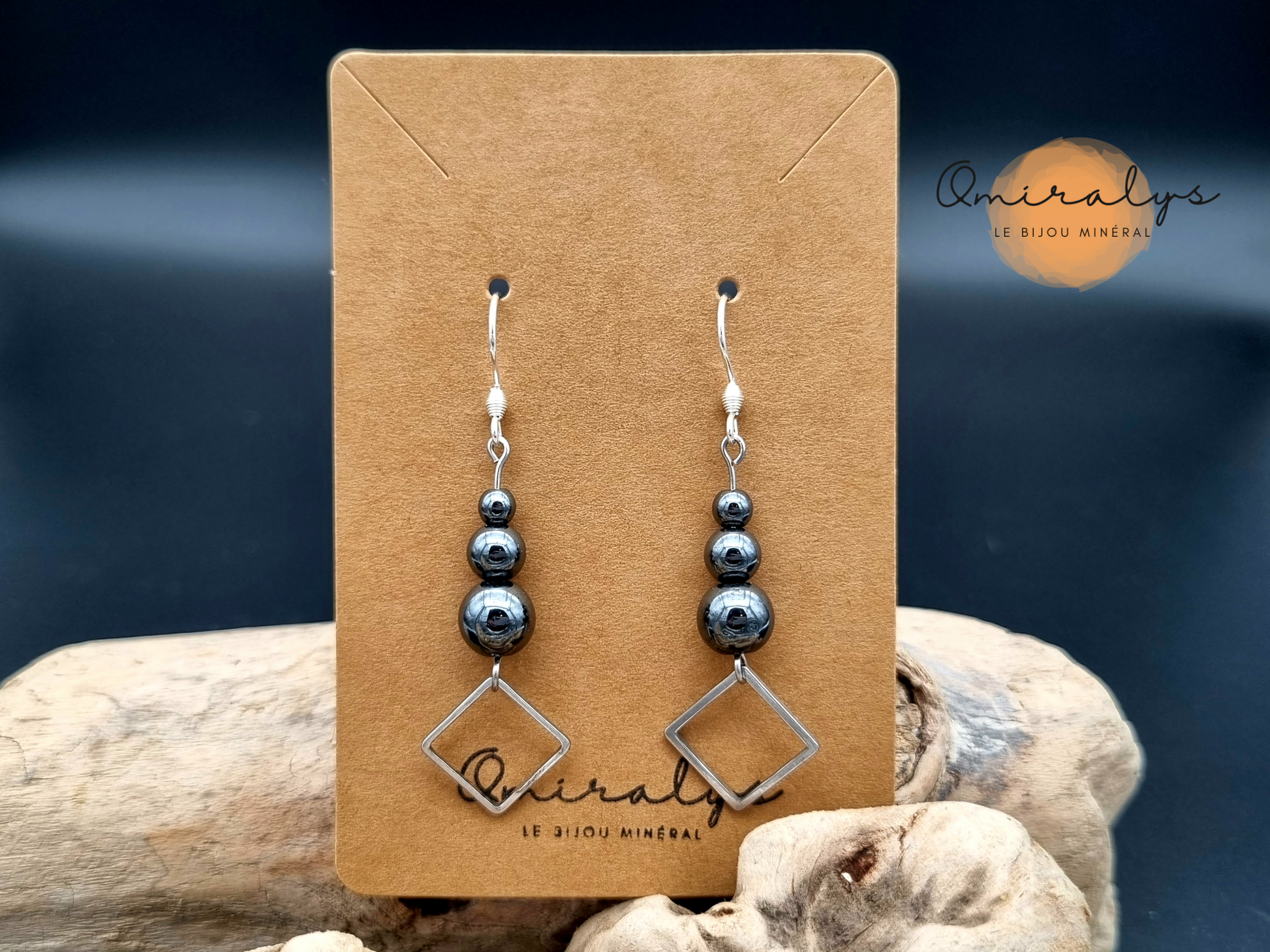 Boucles d'oreilles losanges hématite exposées sur une carte présentoir en carton.