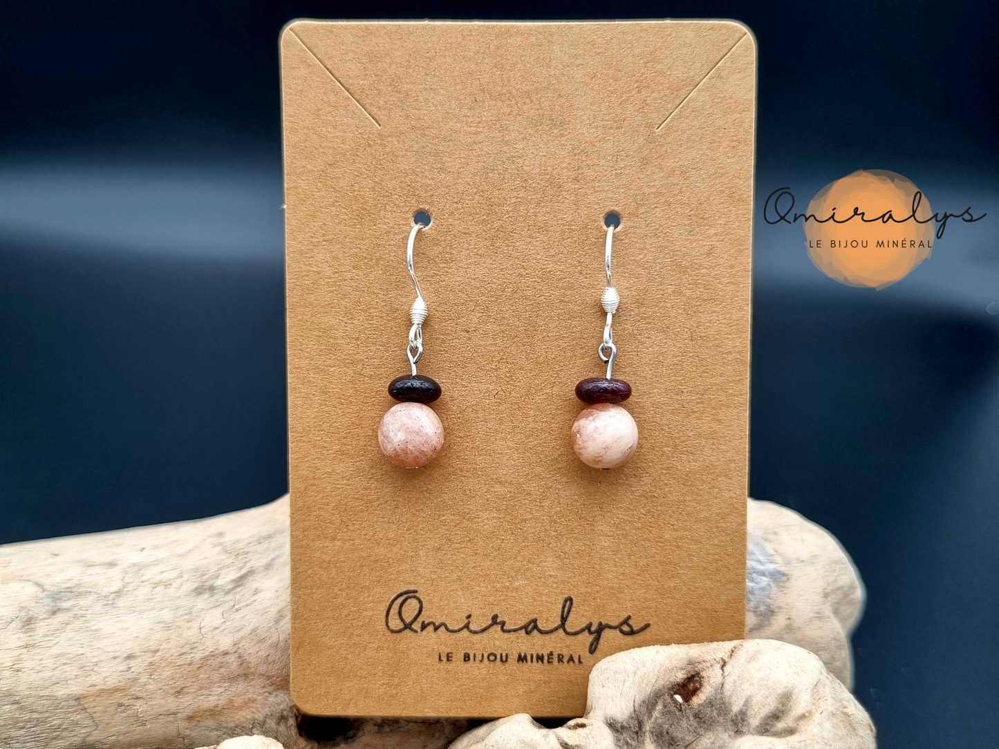 Boucles d'oreilles pierre de lune rose et grenat exposées sur une carte présentoir en carton.