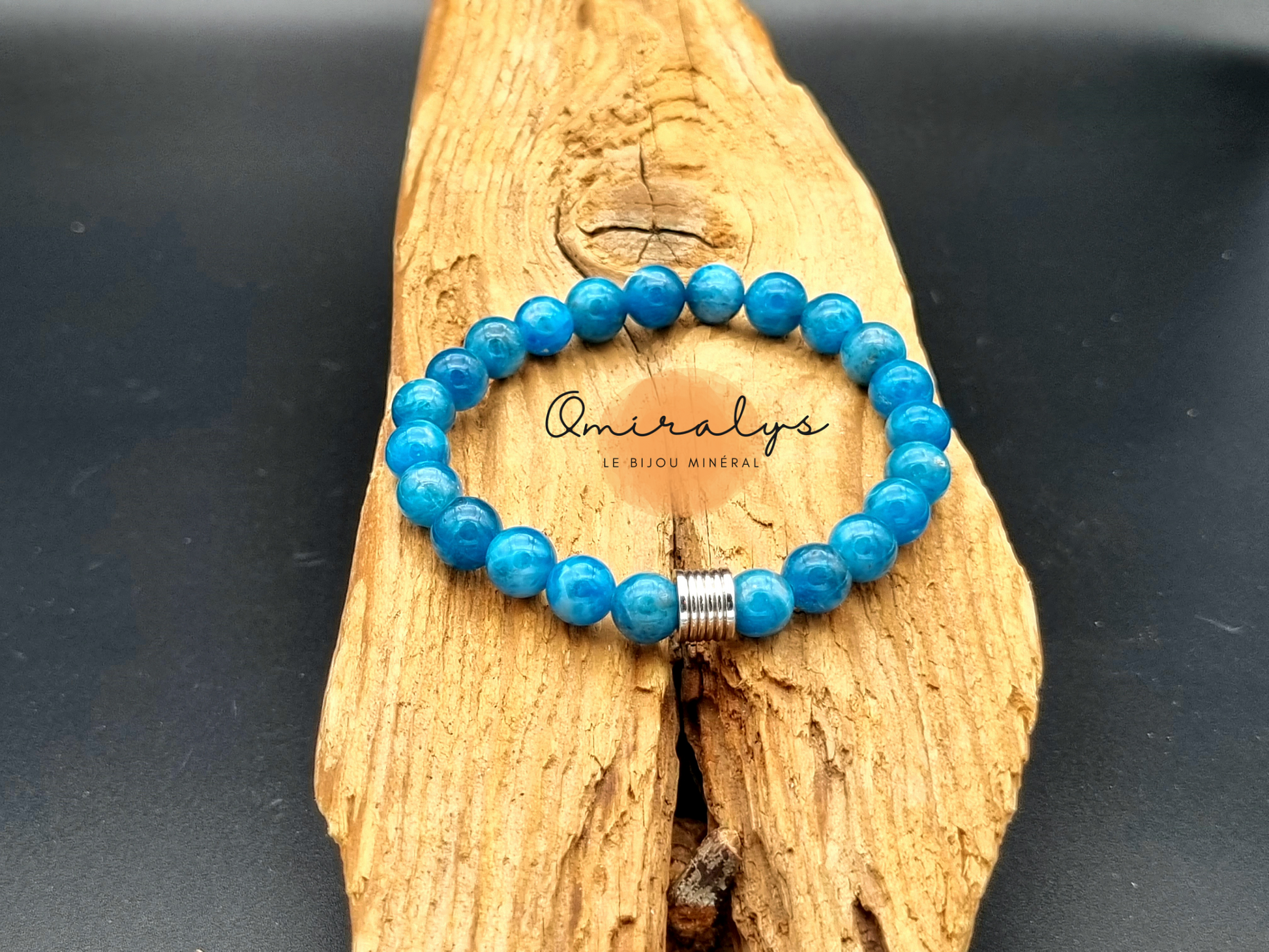 Bracelet en apatite qui repose sur un morceau de bois.