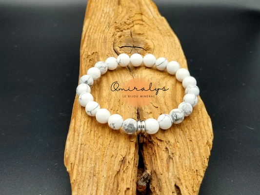 Bracelet Howlite qui repose sur un morceau de bois.