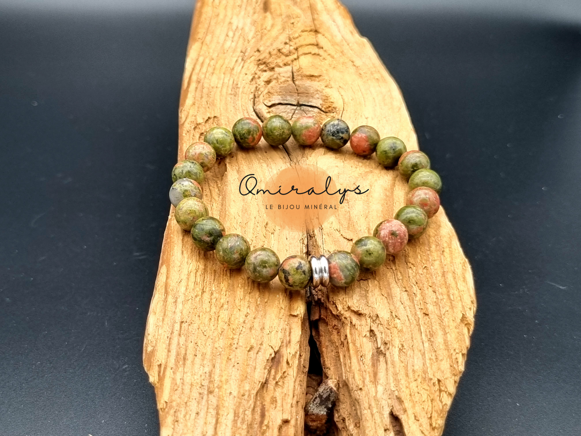 Bracelet Unakite qui repose sur un morceau de bois.