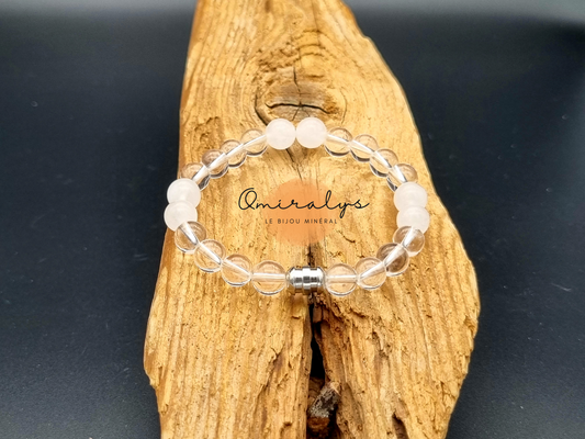 Bracelet cristal de roche et quartz rose qui repose sur un morceau de bois.