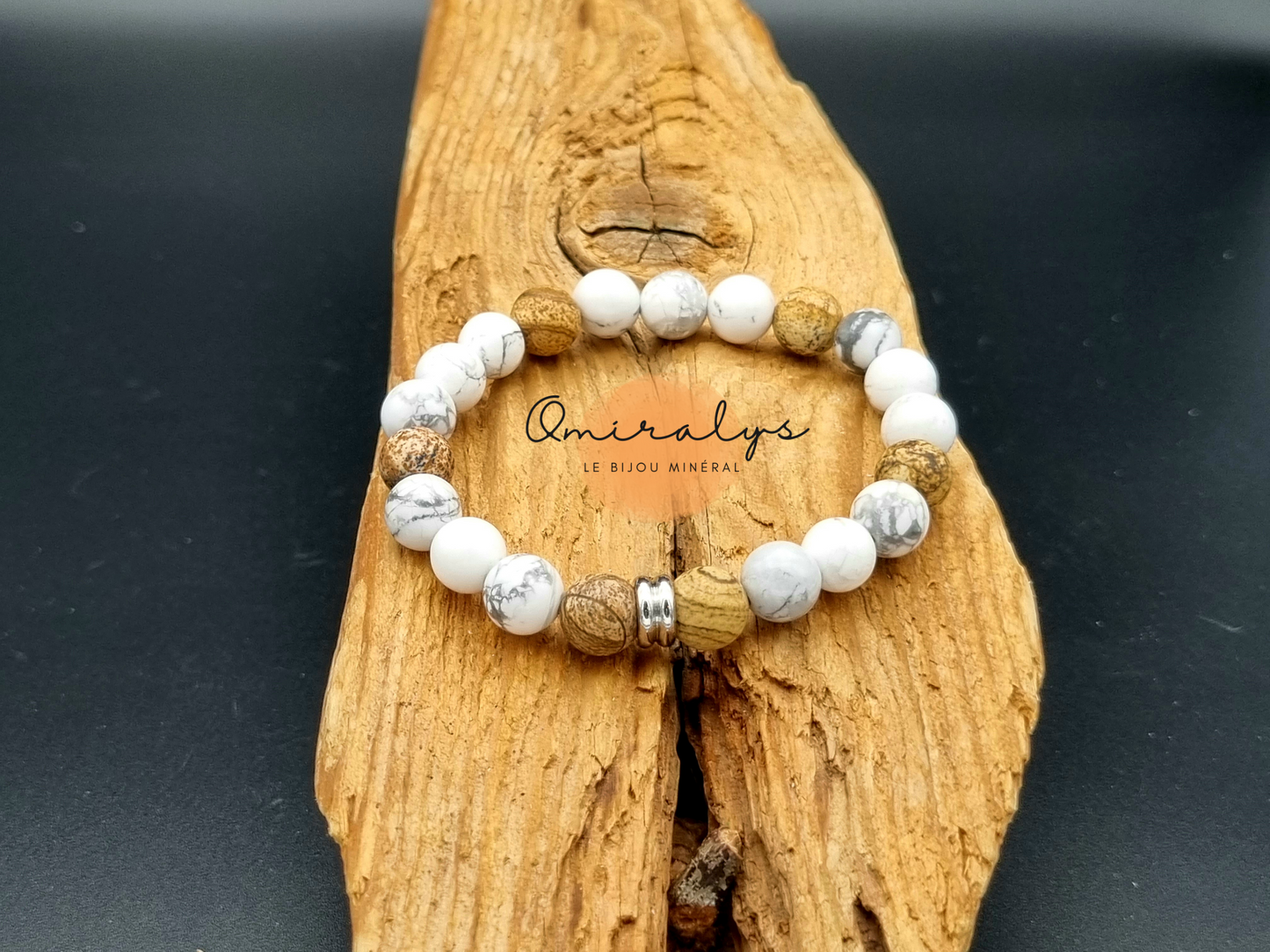 Bracelet howlite blanc et jaspe paysage qui repose sur un morceau de bois.