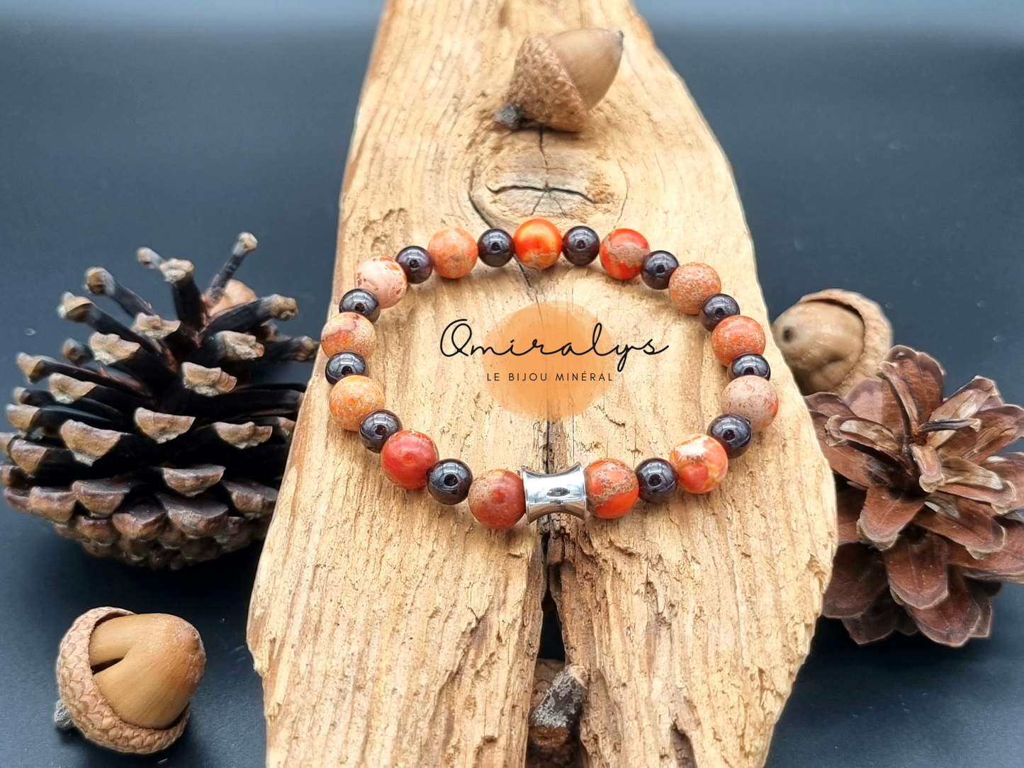 Bracelet jaspe impérial orange et grenat qui repose sur un morceau de bois.