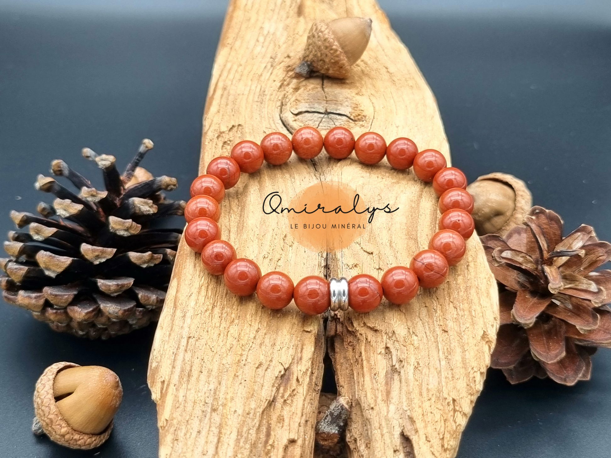 Bracelet jaspe rouge qui repose sur un morceau de bois.