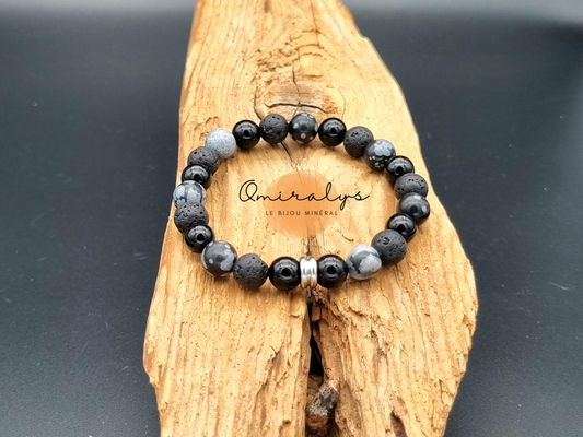 Bracelet onyx, pierre de lave et obsidienne flocon neige qui repose sur un morceau de bois.