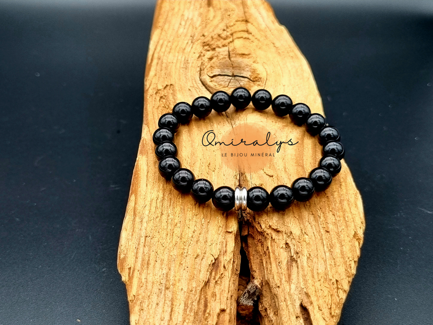 Bracelet onyx qui repose sur un morceau de bois.