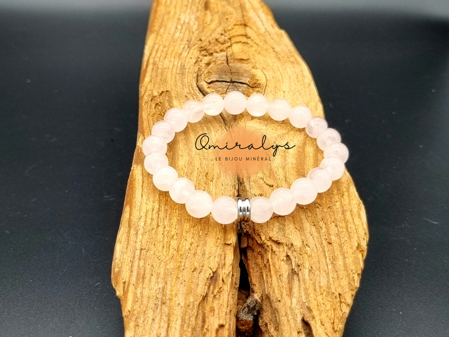 Bracelet quartz rose qui repose sur un morceau de bois.