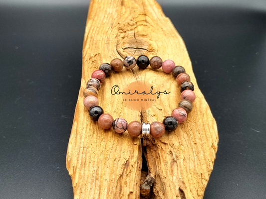 Bracelet rhodonite qui repose sur un morceau de bois.