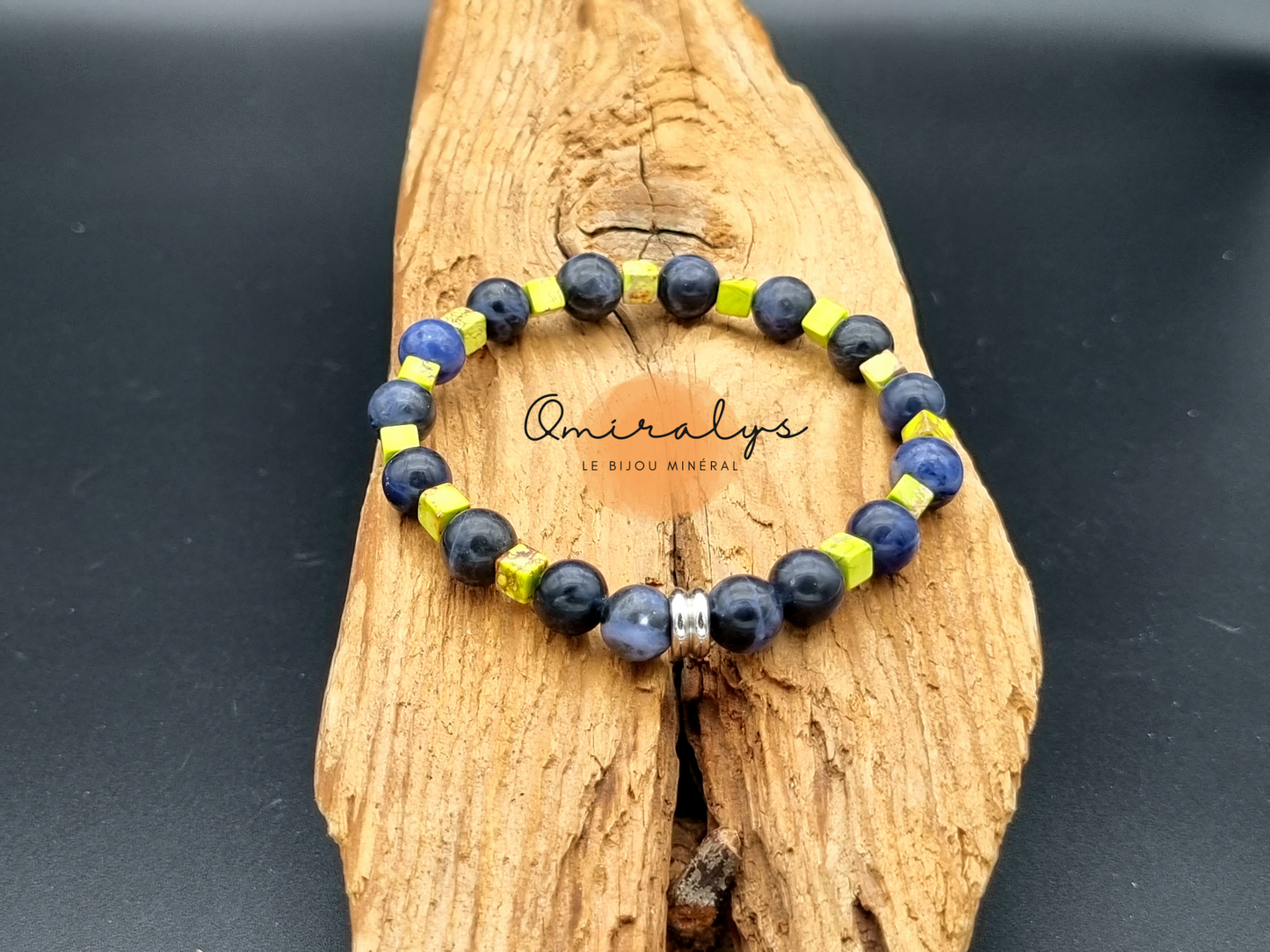 Bracelet sodalite et jaspe impérial vert qui repose sur un morceau de bois. 