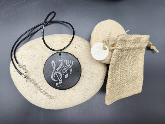 Collier unique Omiralys modèle Ebonique avec pendentif rond noir, clé de sol blanche et reflets pailletés.