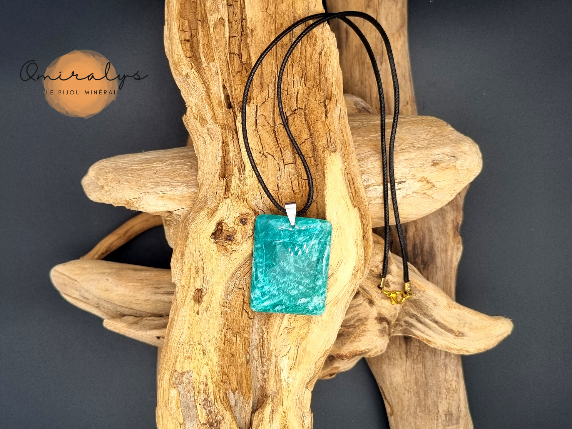 Collier en amazonite présenté sur un morceau de bois flotté.