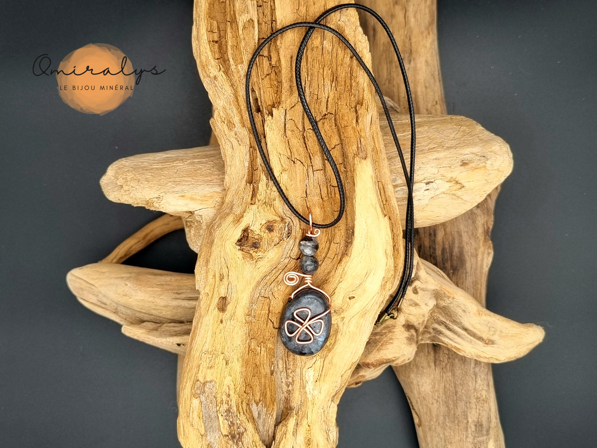 Collier en larvikite présenté sur un morceau de bois flotté