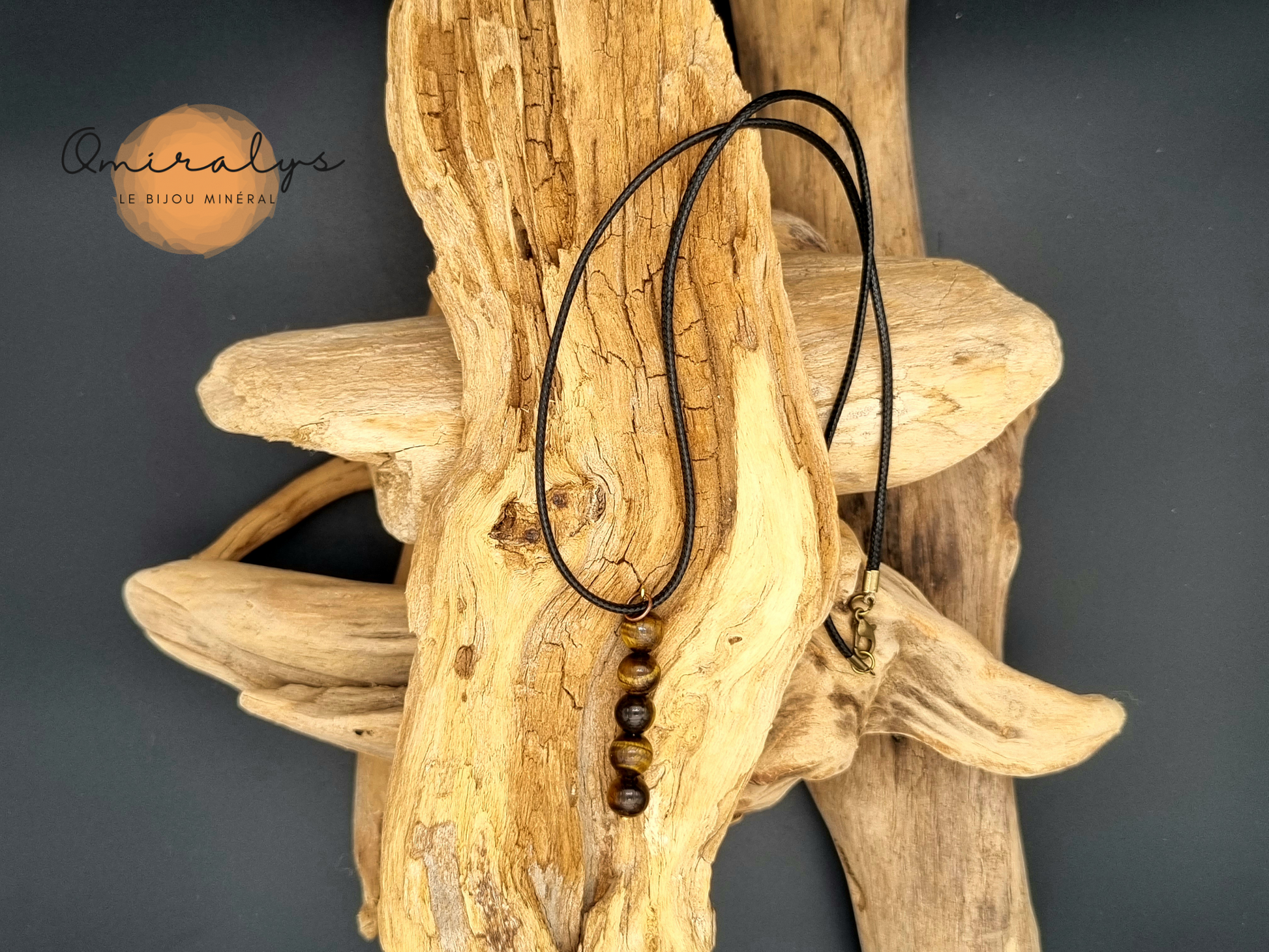 Collier Œil du tigre en perles 8mm présenté sur un morceau de bois flotté