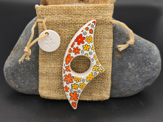 Bague de lecture artisanale décorée de fleurs orange et jaunes, présentée sur un pochon en toile de jute – création Omiralys.