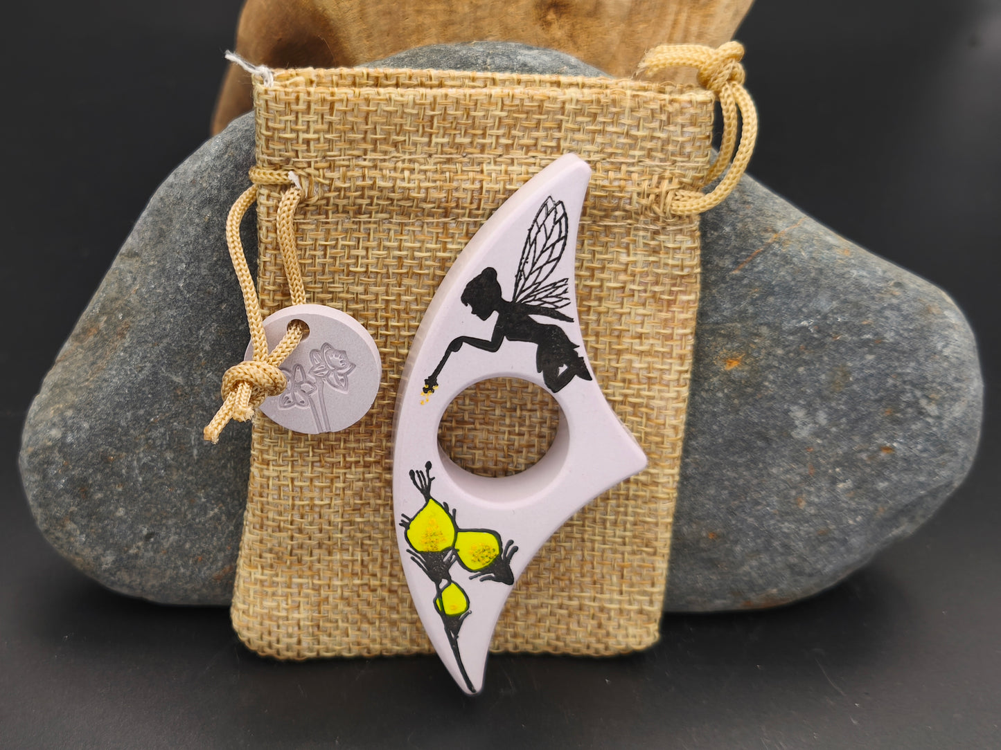 Bague de lecture artisanale Omiralys mauve fée nocturne avec fée noire et fleurs jaunes sur son pochon en toile de jute