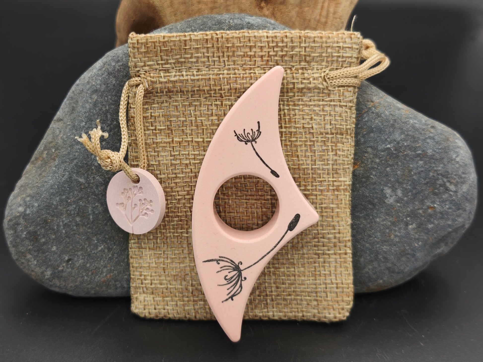 Bague de lecture artisanale Omiralys saumon doux avec décor fleurs légères noires sur son pochon en toile de jute.