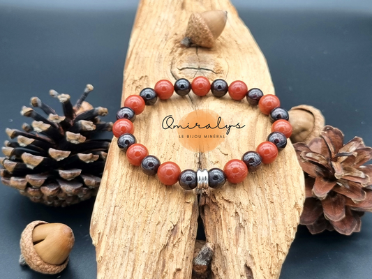 bracelet jaspe rouge et grenat qui repose sur un morceau de bois.